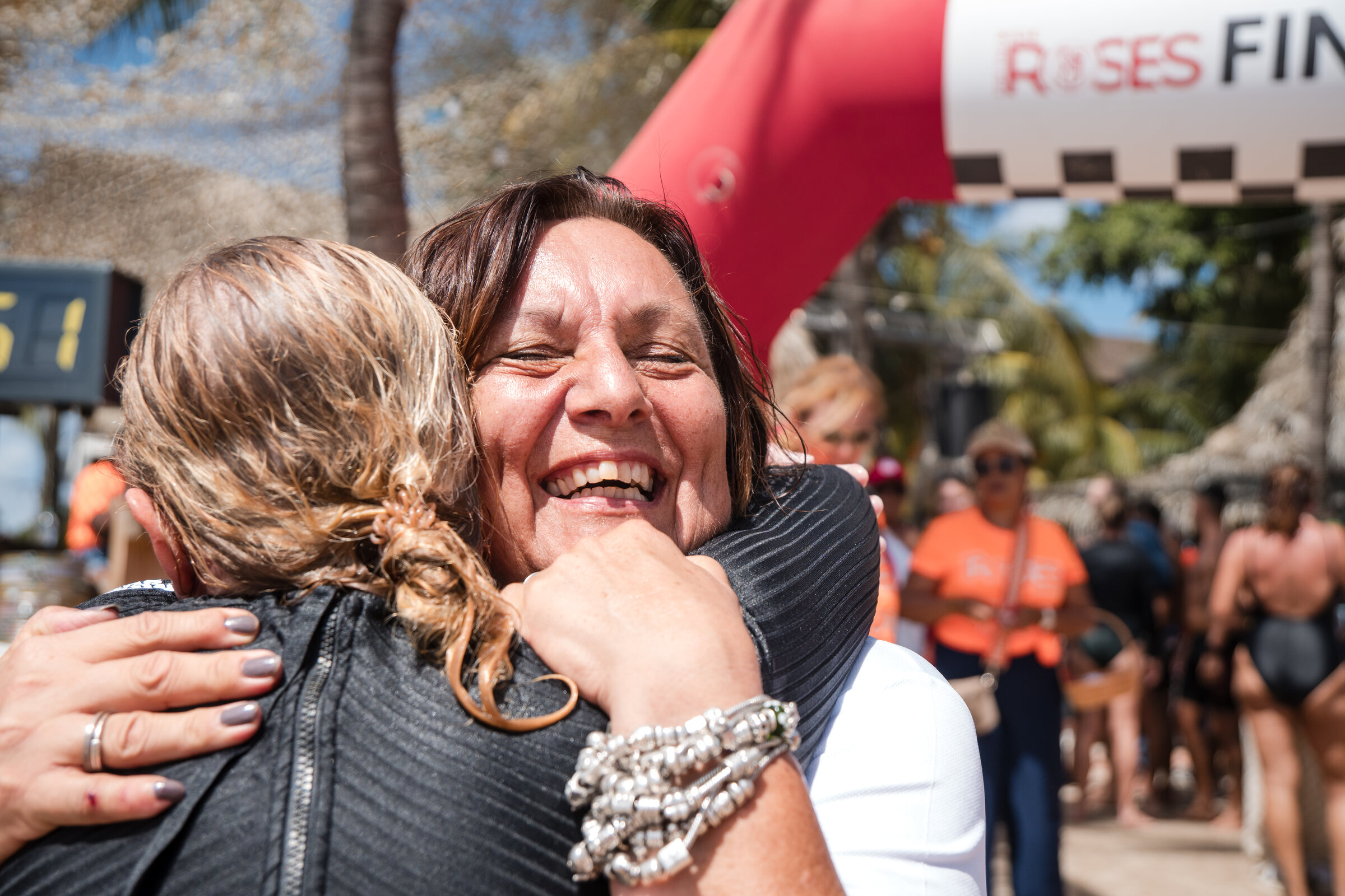 Two women embracing and laughing at the Ride for the Roses finish line in Curacao