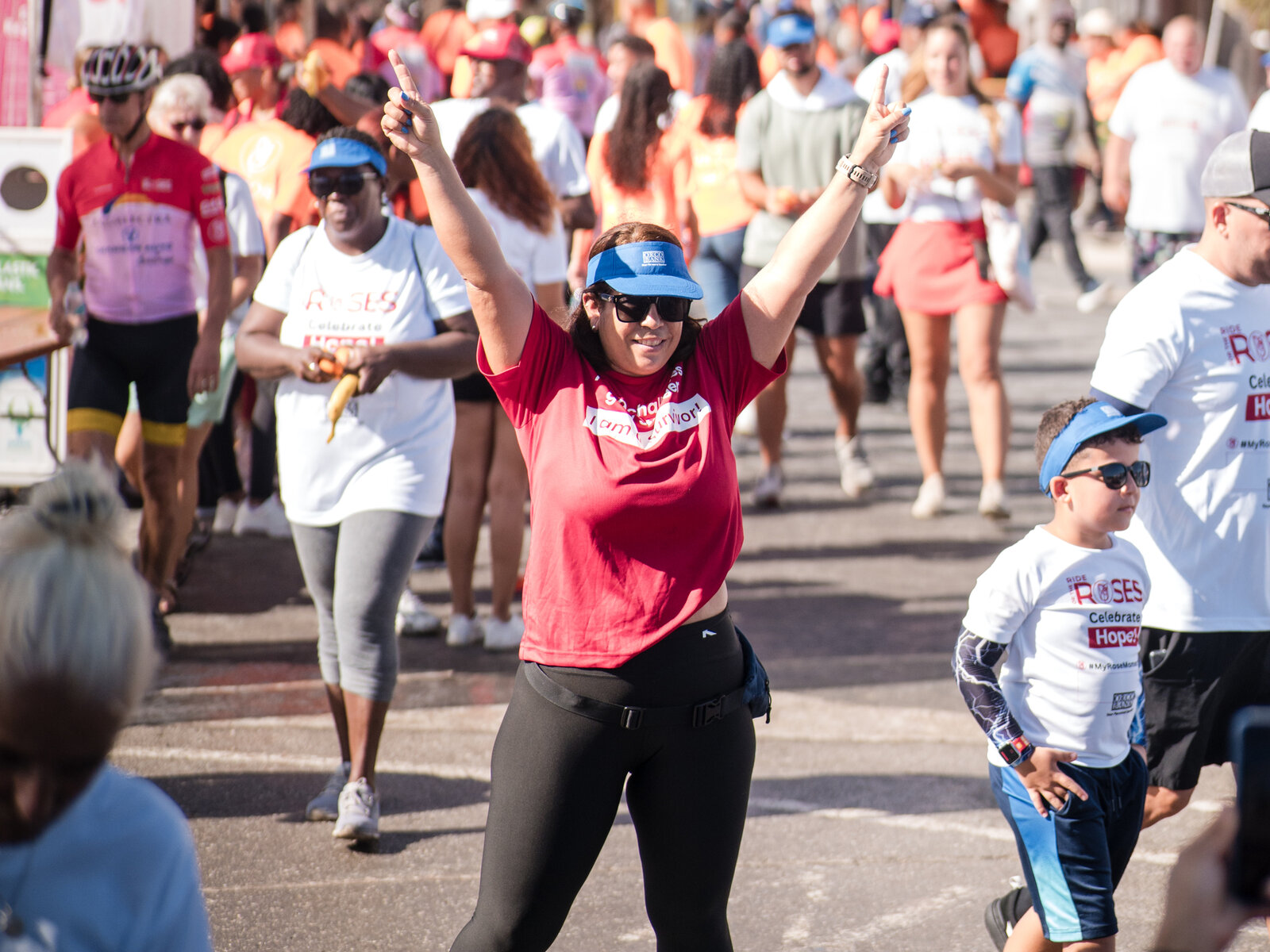 A participant celebrating with both arms raised as she crosses the Ride for the Roses finish line in Curacao