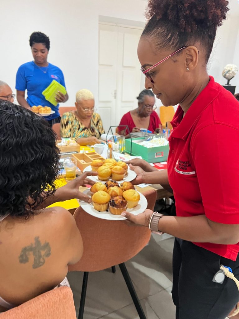 A PWF staff member serving muffins to participants during a therapy and recreation session