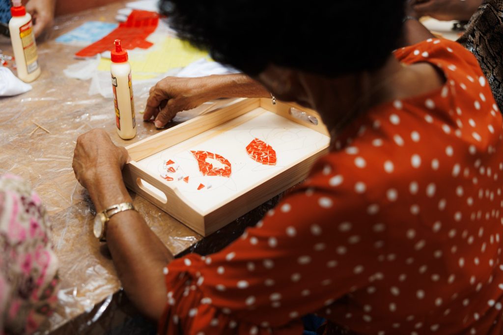 A participant arranging red mosaic pieces on a wooden serving tray